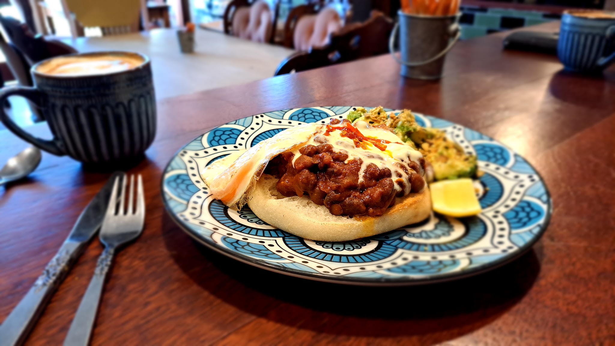 Breakfast of beans, poached egg and avocado on toast with a flat white