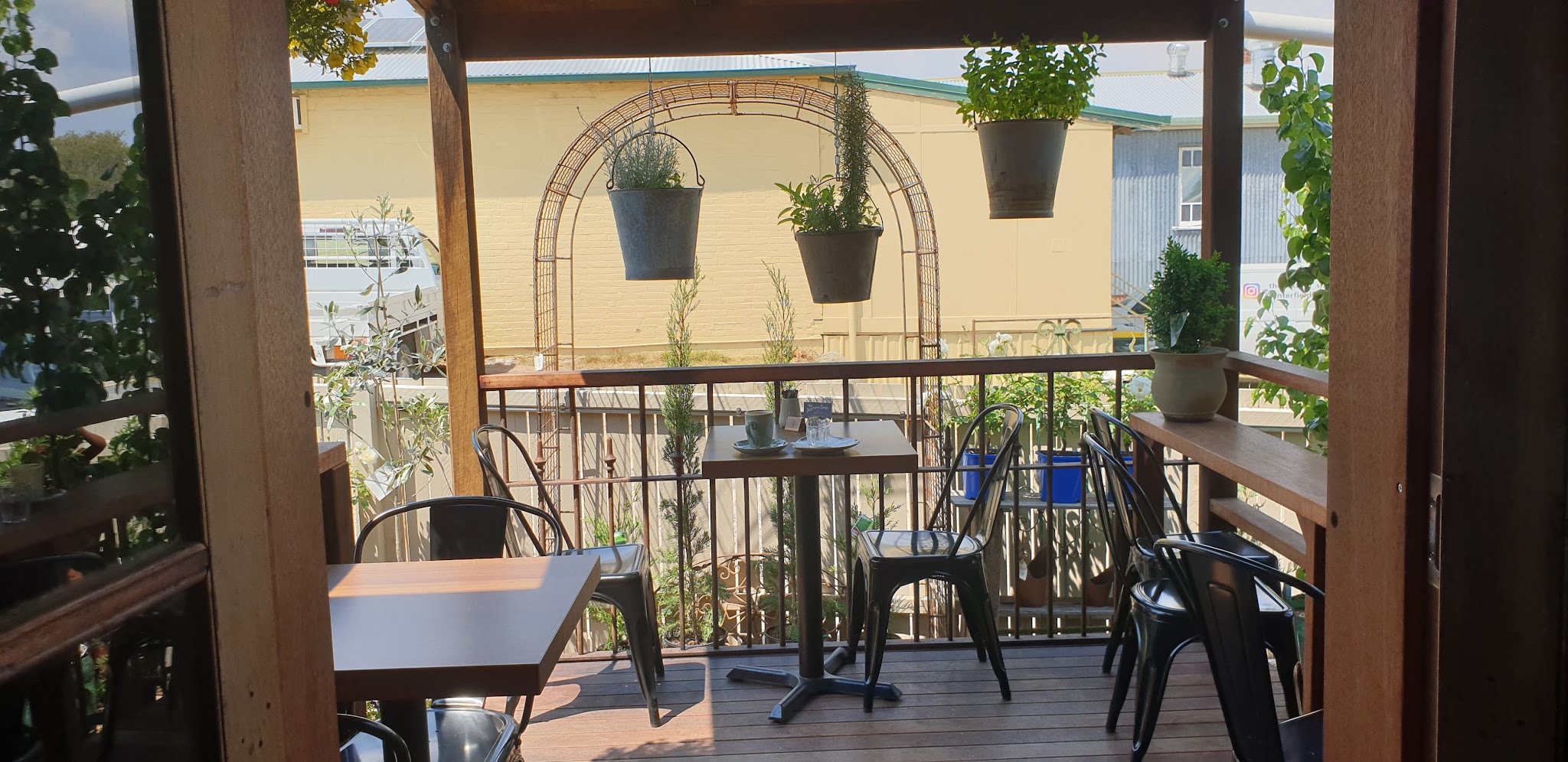 Outdoor deck with café tables under an arch of hanging planters